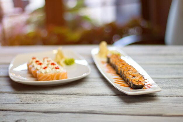 Rolos de sushi em pratos brancos. Sushi com caviar e molho. Refeição japonesa em restaurante local. Atum fresco ou salmão fumado.