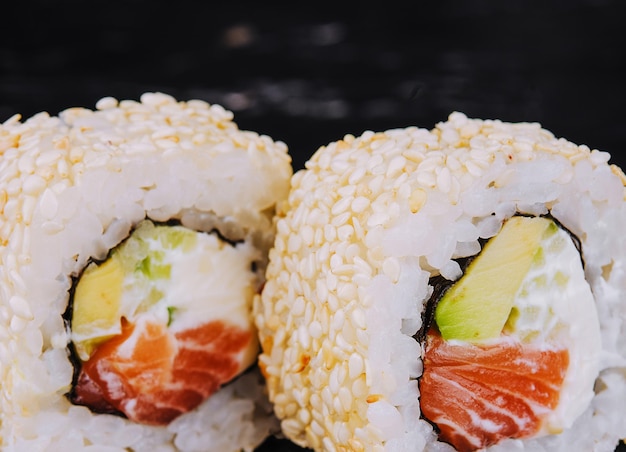 Rolos de sushi japonês com salmão em arroz e gergelim