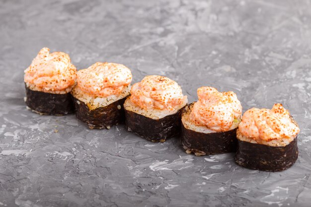 Rolos de sushi maki japonês com ovas de peixe voador, queijo em fundo preto de concreto