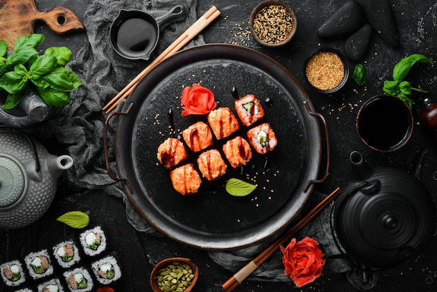 Rolos de sushi tradicionais apetitosos em uma placa de pedra preta. culinária japonesa. vista do topo.