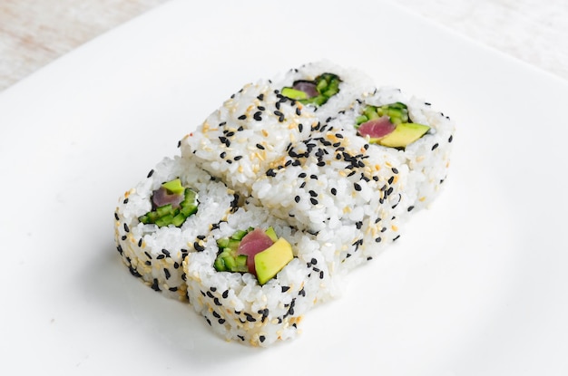 Rolos de sushi tradicionais e maki com gergelim, abacate e peixe. Comida japonesa. Vista do topo. Em um fundo branco.