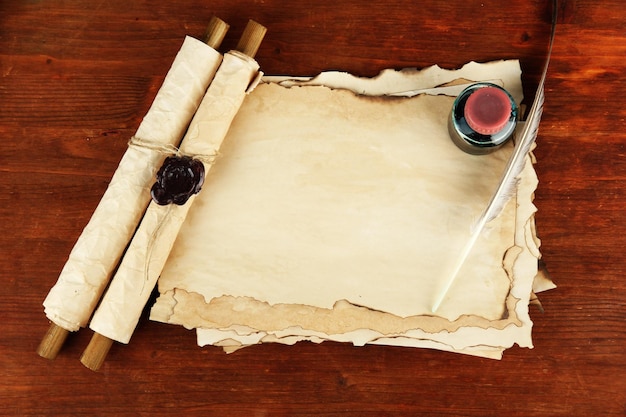 Rolos de tinta de papel antigos e penas em fundo de madeira