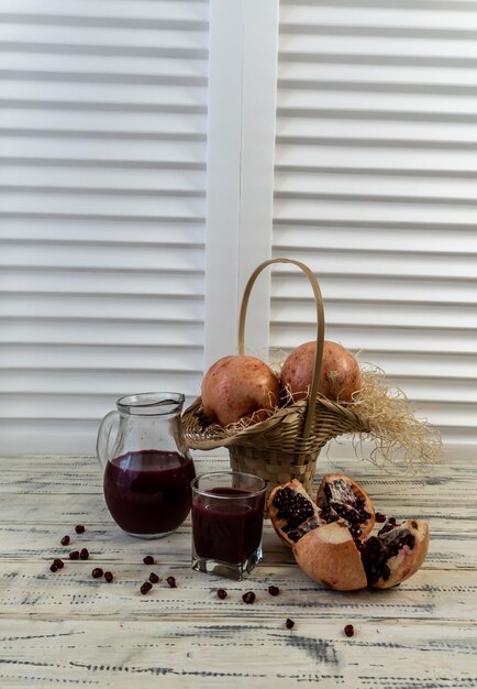 Romã em uma cesta e na mesa em um fundo de madeira Suco de romã