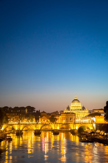 Roma, itália - junho de 2020: panorama do pôr do sol na ponte do rio tibre com a cúpula da catedral de são pedro (cidade do vaticano) no fundo - roma, itália