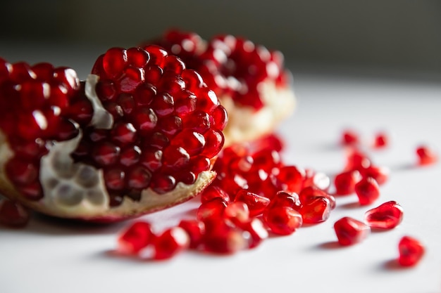 Romã madura vermelha na mesa branca close-up. Imagem macro, profundidade de campo rasa. Fundo de frutas de verão