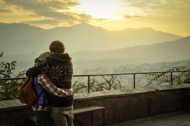 Foto romace del hombre y de la muchacha en la montaña con salida del sol.