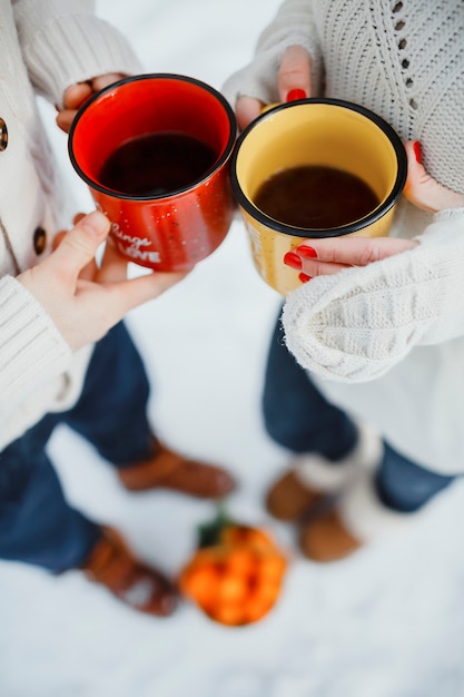 Foto romance de ano novo, duas pessoas com canecas de chá na floresta de inverno