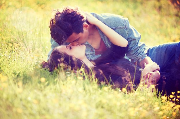 Romance juvenil Imagen de estilo vintage de una pareja joven besándose románticamente en un campo de verano