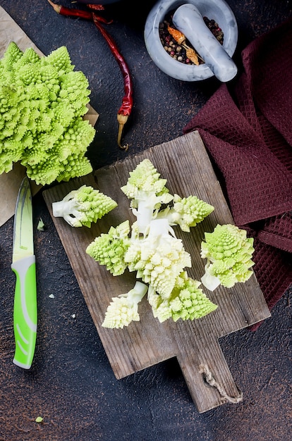 Romanesco verde fresco, repollo orgánico crudo listo para cocinar sobre una tabla para cortar