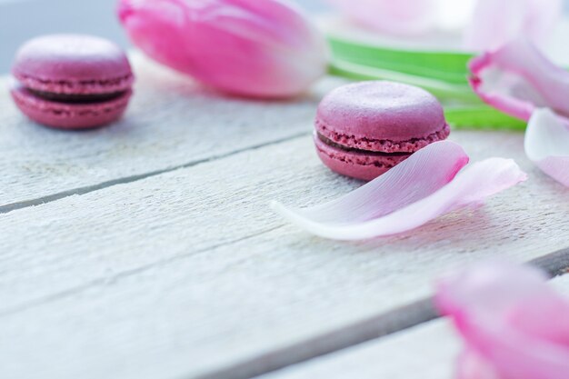 Romántica composición delicada con flores rosas y pasteles de macarrón.