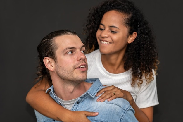 Romántica joven pareja feliz hombre caucásico y mujer afroamericana sonríen y se divierten abrazo juntos en el día de san valentín sobre fondo negro