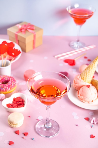 Romántica mesa de postres dulces con una copa de vino rosado waffles donut helado macaron lollipop dulces concepto de San Valentín