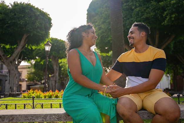 Romántica pareja afroamericana sentada en un banco