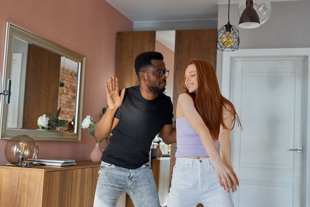 Romántica pareja divertida bailando en casa, atractiva pelirroja y guapo