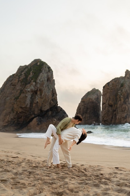 Romántica pareja enamorada bailando en la playa disfrutando de su cita en la orilla del océano espacio libre en toda su longitud