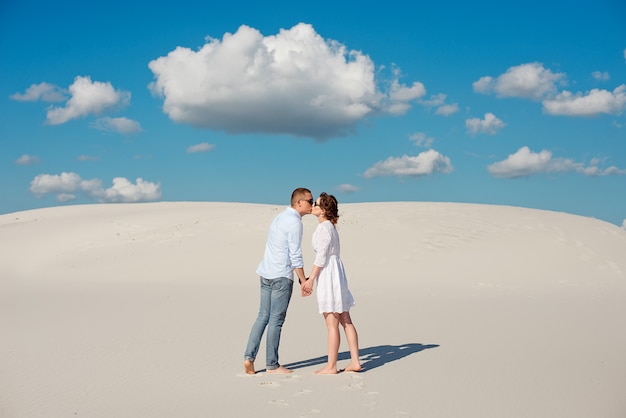 Romántica pareja de enamorados beso en la arena blanca en el desierto