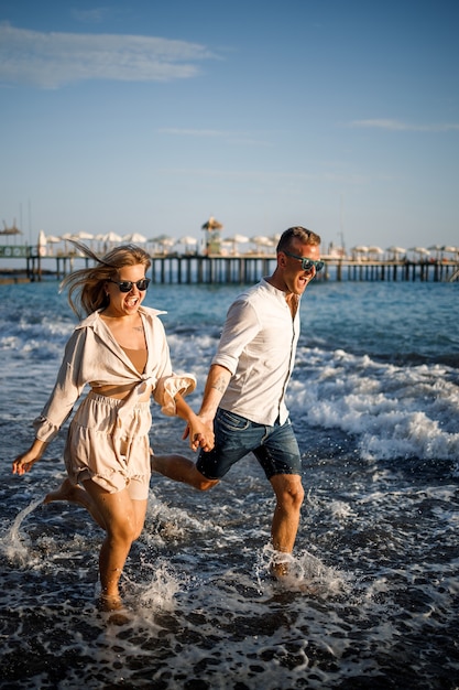 Romántica pareja de jóvenes enamorados juntos en la arena paseos por la playa del mar Mediterráneo. Vacaciones de verano en un país cálido.