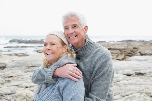 Romántica pareja senior junto en la playa rocosa