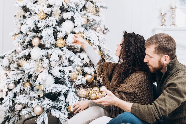 Romántica pareja sonriente se sienta cerca del árbol de Navidad. Navidad y año nuevo concepto