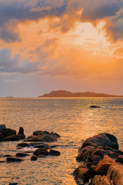 Romántico amanecer en la playa Capriccioli de Costa Smeralda en la isla de Cerdeña en Italia. Cielo con nubes. Piedras y rocas.