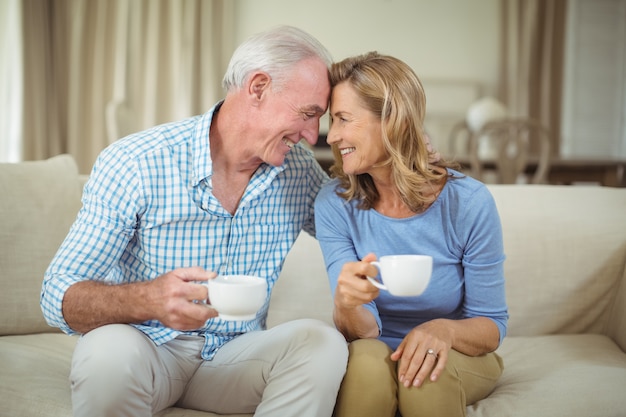 Romântico casal sênior tomando café na sala de estar