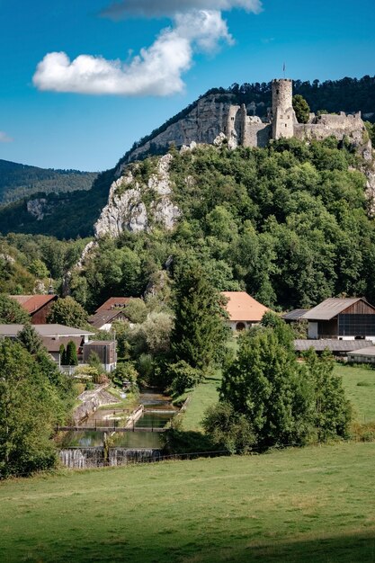 Romántico castillo en la cima de una colina en un valle montañoso en los Alpes de Suiza con un cielo azul de fondo, pequeño pueblo bajo la roca