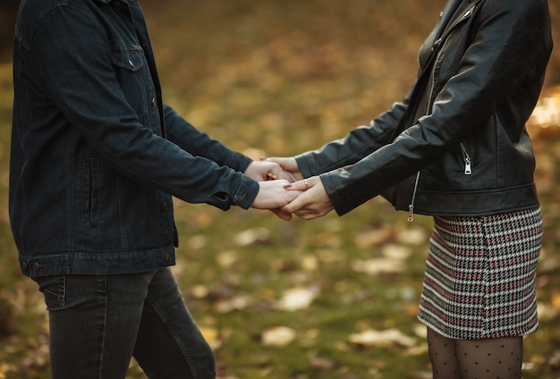 Romântico, conceito de amor. Jovem casal apaixonado de mãos dadas sobre um fundo desfocado de folhas de outono caídas no parque. Data Romantica