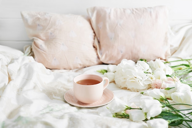 Romântico dia dos namorados Café da manhã na cama com xícara de chá e flores na cama