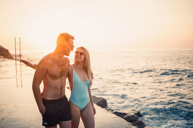 Romântico jovem casal apaixonado caminhando juntos ao pôr do sol ao longo da praia mediterrânea Férias de verão em um país quente Casal feliz de férias na Turquia Foco seletivo