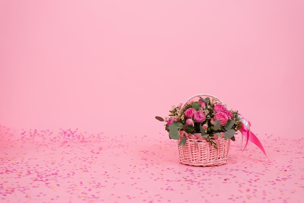 Romántico ramo de rosas rosadas y eucalipto en una canasta sobre un fondo rosa con confeti Regalo de cumpleaños Día de la mujer Día de la mamá Día de los enamorados