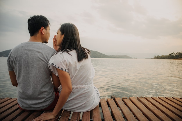 Romantische asiatische Paare, die flüstern und die Seesicht genießen.