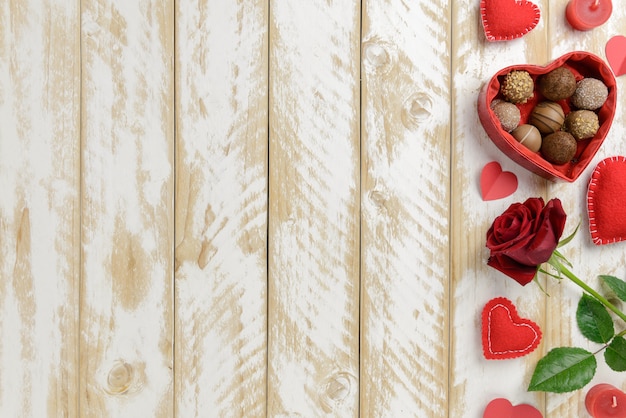 Romantische Dekoration zum Valentinstag mit Rosen und Schokolade auf einem weißen Holztisch. Draufsicht, Kopierraum.