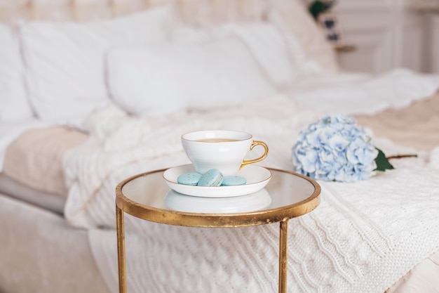 Romantische Frühstückstasse Teemakronen und blaue Hortensienblume im Schlafzimmer