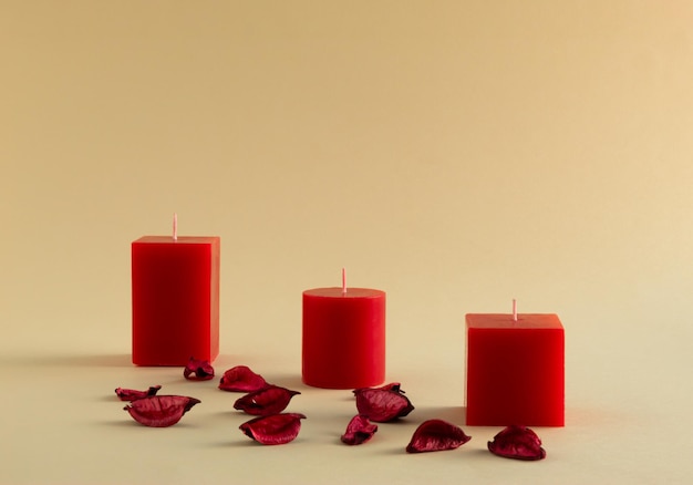 Romantische Komposition mit roten Kerzen und Blütenblättern auf hellbeigem Hintergrund. Idee für eine Valentinstagskarte. Platz kopieren.