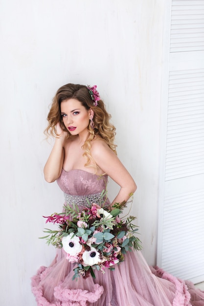 Romantische Modefrau in einem rosa Kleid und Blumenstrauß.