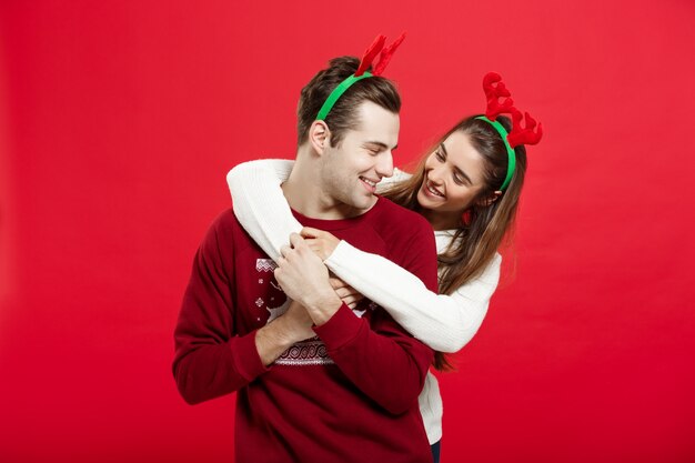 Romantische Paare in den Weihnachtsstrickjacken, die sich huging sind.