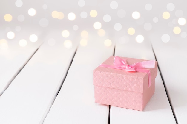 Romantischer festlicher Hintergrund mit Geschenk und rosafarbenem Geschenk auf weißem Tisch mit Bokeh