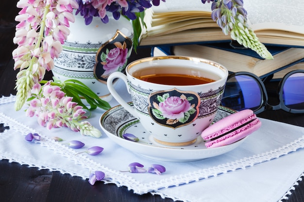 Romantischer Hintergrund mit Tasse Teeblumen und offenem Buch über weißem Tisch