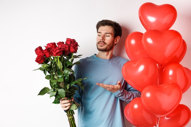 Romantischer Kerl, der Strauß roter Rosen zeigt