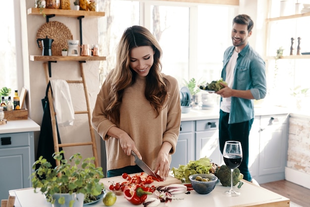 Romantisches Abendessen. Schönes junges Paar, das Abendessen kocht, während es zu Hause in der Küche steht