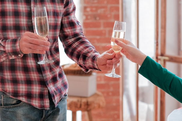 Romantisches Date. Kurzer Schuss eines Mannes im karierten Hemd, der seiner Freundin ein Glas Champagner gibt.