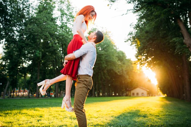 Romantisches Date, Umarmung des Liebespaares, Treffen im Sommerpark. Attraktive Frau und junger Mann glücklich zusammen