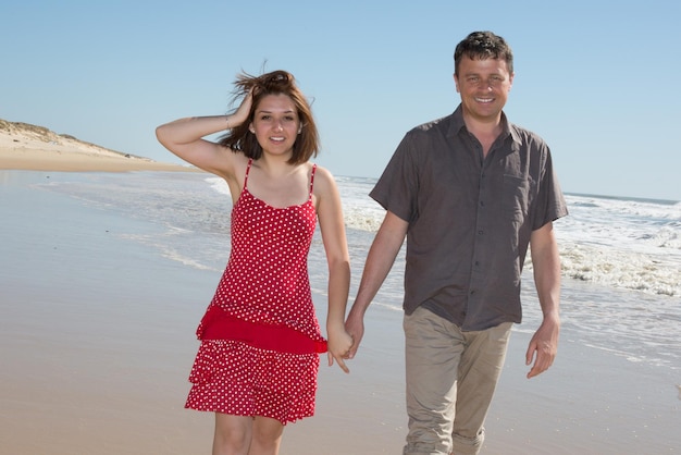 Romantisches fröhliches Paar im Urlaub am Strand entlang spazieren