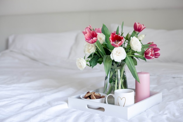 Romantisches Frühstück im Bett. Blumenstrauß. Rosen und Tulpen.