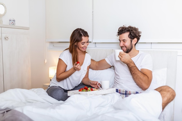 Romantisches Frühstück im Bett Mann bereitet sich auf seine Frau vor, sie war sehr glücklich, Junges schönes Paar im Bett beim Frühstück und Kaffee im Bett