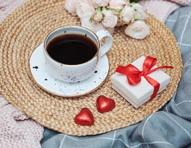 Romantisches Frühstück mit Kaffee, Geschenkbox und Rosenblüten.