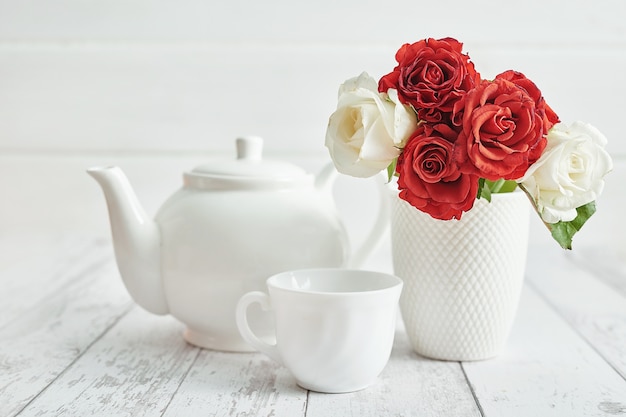 romantisches Frühstück mit roten Rosen und Teekanne.