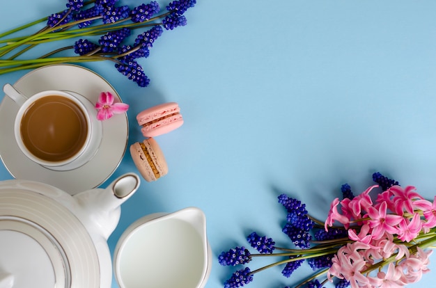 Romantisches Frühstückskonzept. Tasse Kaffee mit Milch, Makronen, Milchglas auf Pastellblau