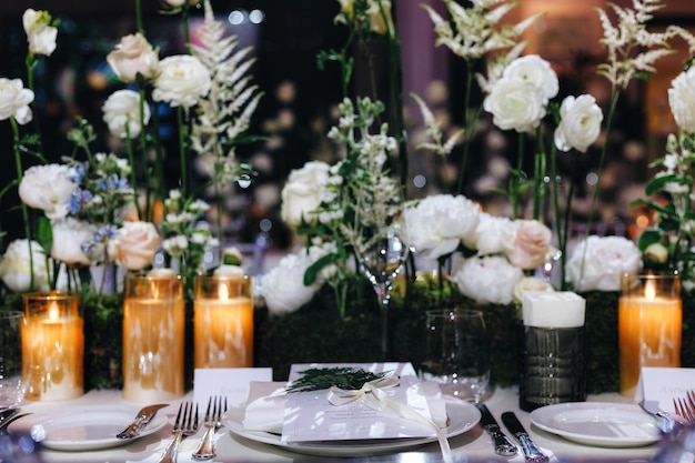 Romantisches Hochzeitstischdekorationsdekor mit großen üppigen Blumensträußen einschließlich weißer Rosen ranunc ...