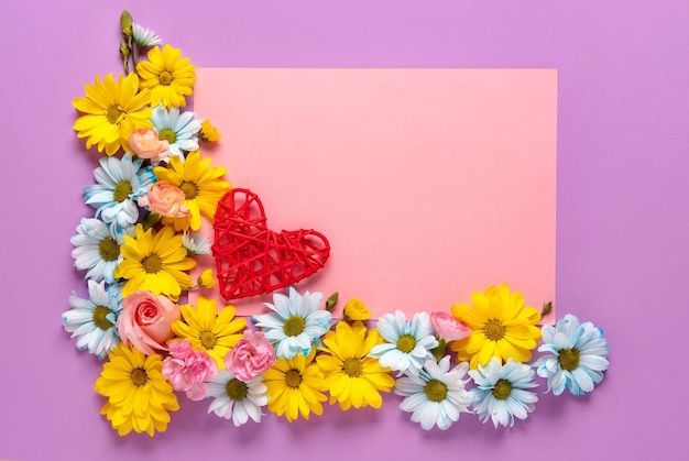 Romantisches Konzept des Valentinstags oder der Hochzeit mit Blumen und rotem Herzen auf rosa Hintergrund. Draufsicht, Kopierraum.